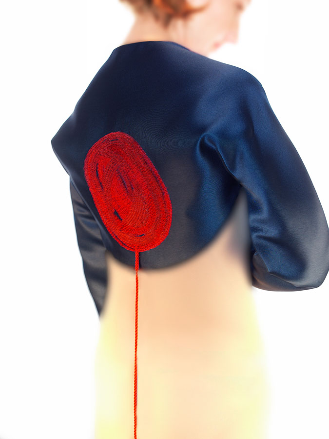 Geoffrey Beene black satin shrug with red silk embroidered yarn ball and cord detail.